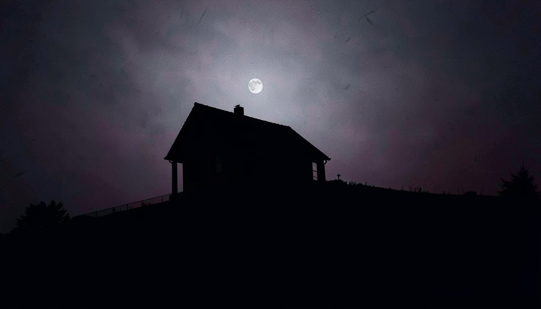 Silhouetted house on a hill under a pale moon, dark navy and silver duotone, eerie quiet mood
