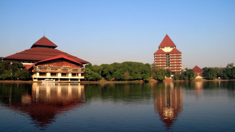 Large tiered-roof buildings beside a calm lake under blue sky, red and green tones, tranquil mood